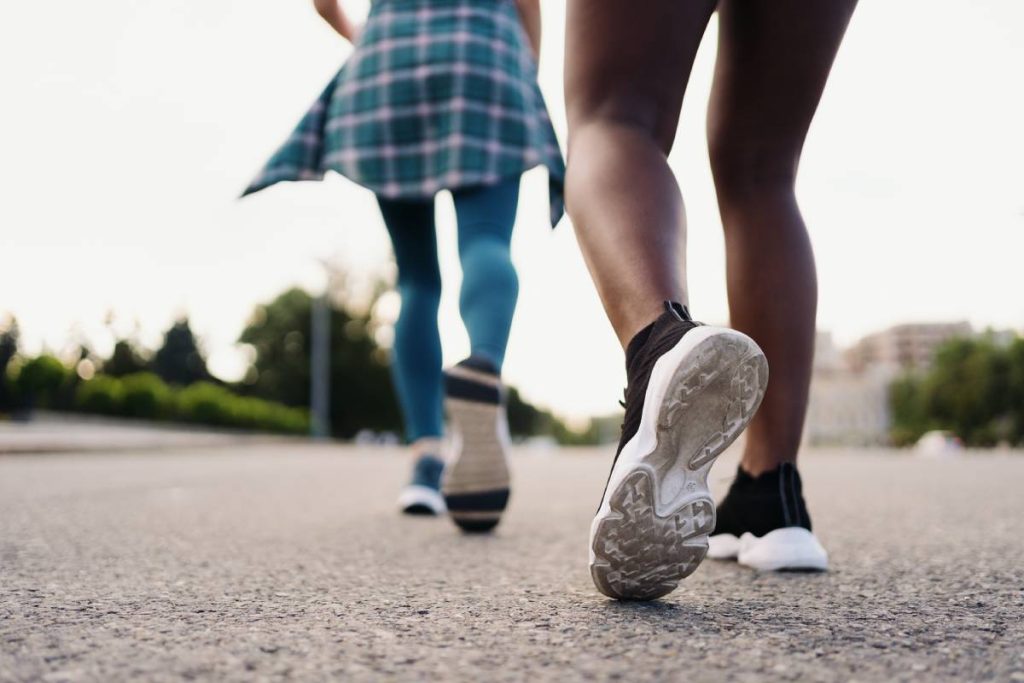 Two multiethnic girls legs running through the city streets, outdoor communicating.