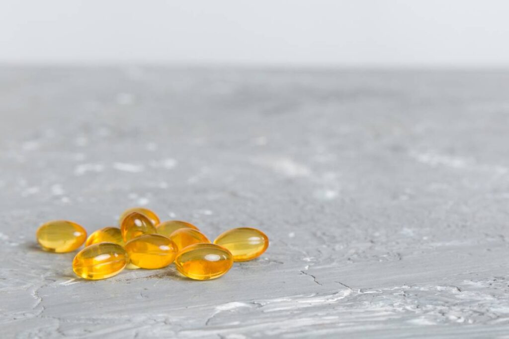 Cod liver oil omega 3 gel capsules on colored background with copy space. Heap of Omega 3 soft gel capsules